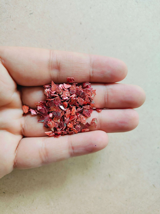 Hand holding red crystal chips for resin art, perfect for crafting and decorating vibrant resin projects