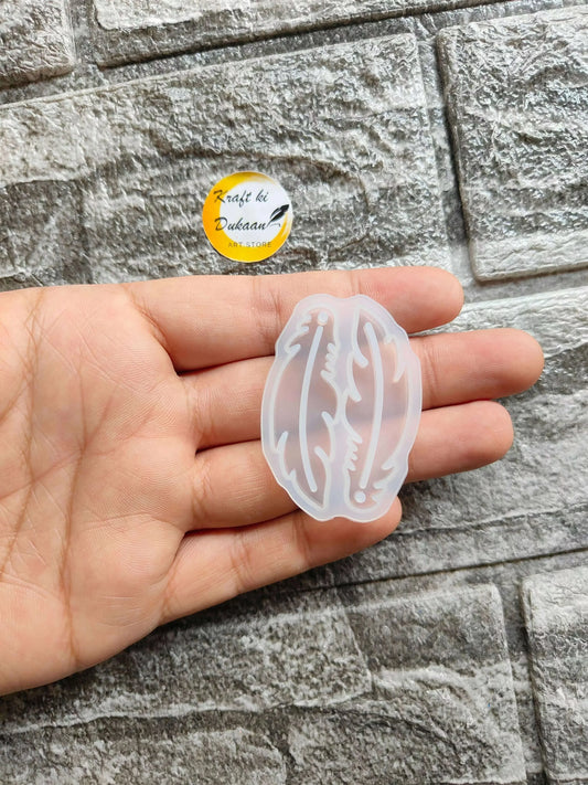 Earring mould A3 in translucent light-blue plastic, held in hand with wing design.