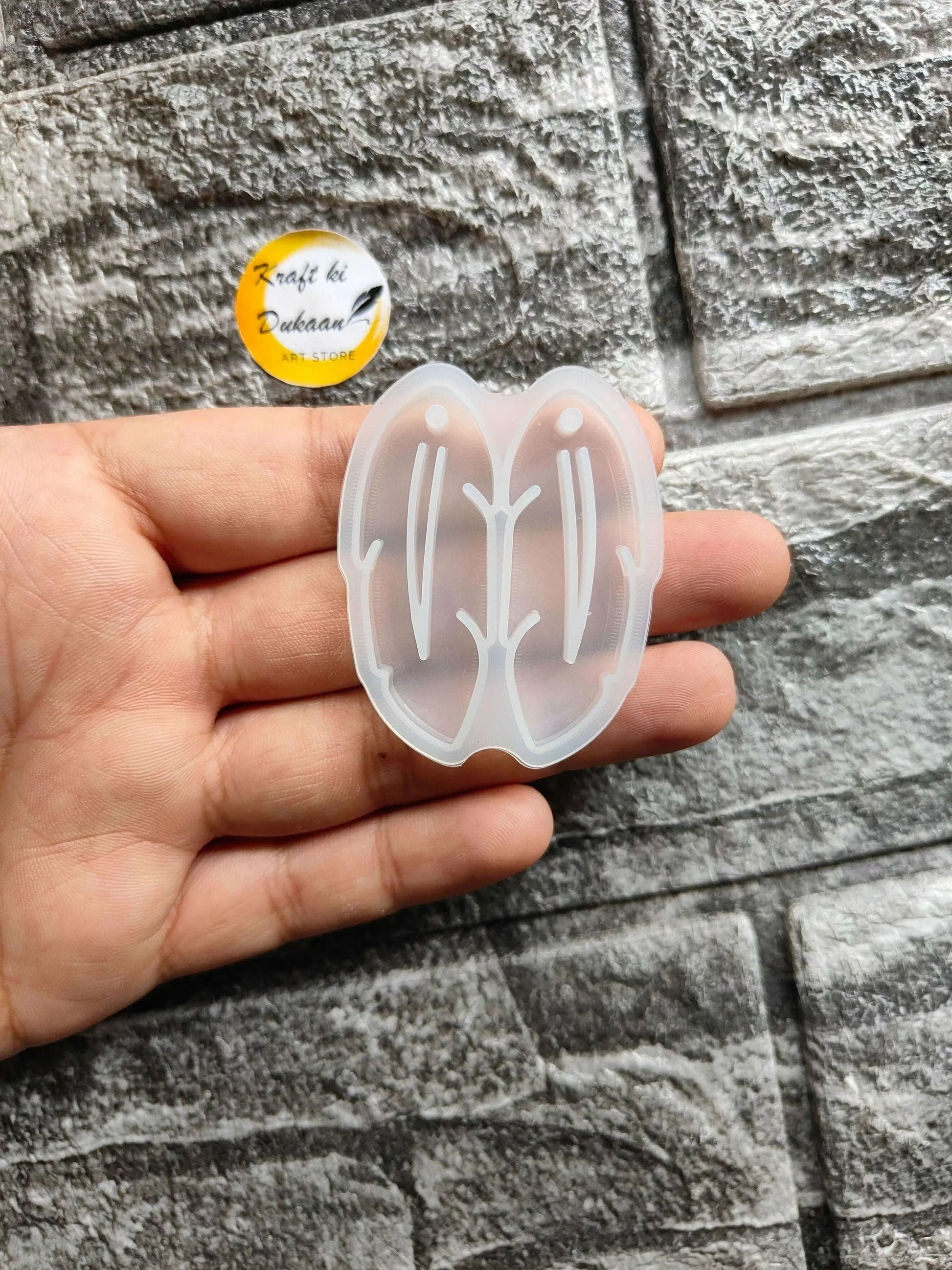Earring Mould A2 in hand — translucent white butterfly silicone mold with stud outlines