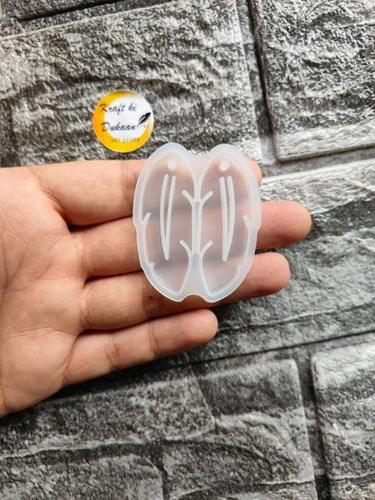 Earring Mould A2 in hand — translucent white butterfly silicone mold with stud outlines
