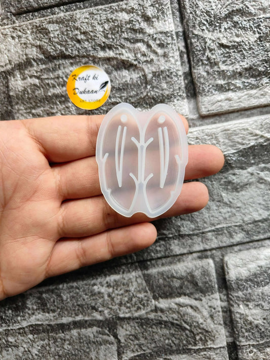 Earring Mould A2 in hand — translucent white butterfly silicone mold with stud outlines