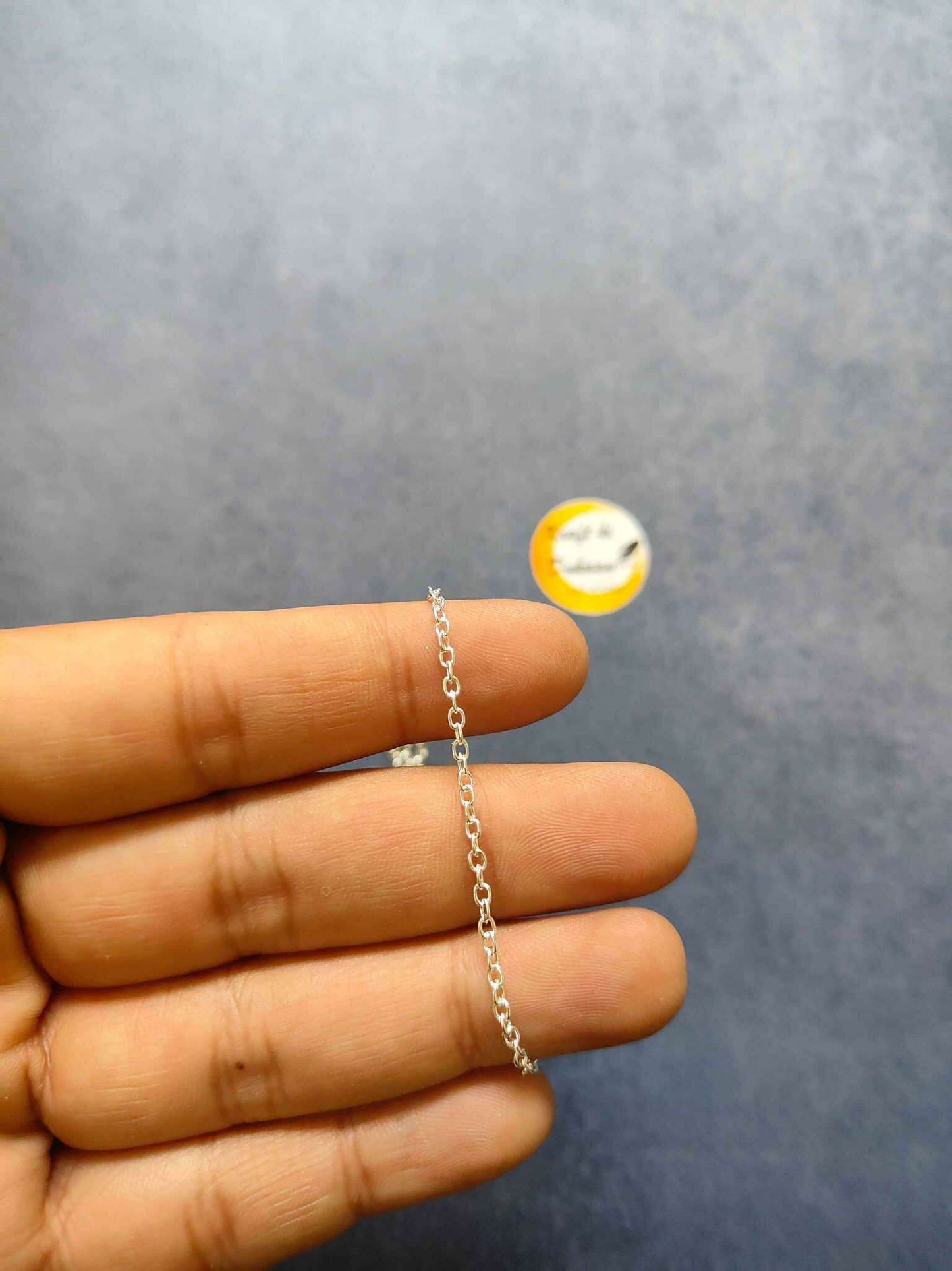 Silver short chain necklace, single small-link chain held in hand