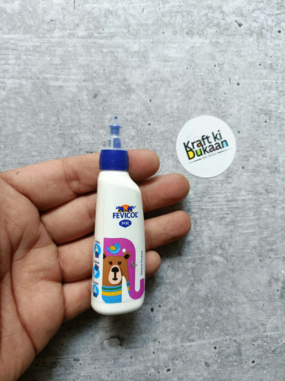 Fevicol MR white glue bottle held in hand, blue cap and bear artwork
