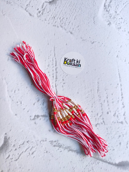 Red rakhi dori with gold bead accents and dangling tassel
