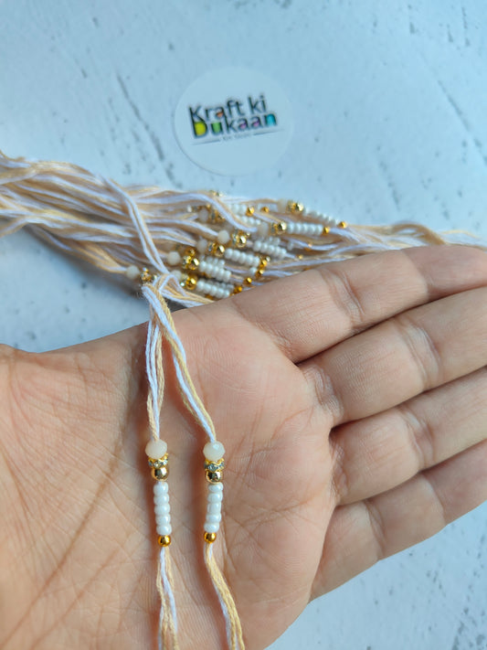 Beaded rakhi dori strings with off-white thread shown in hand