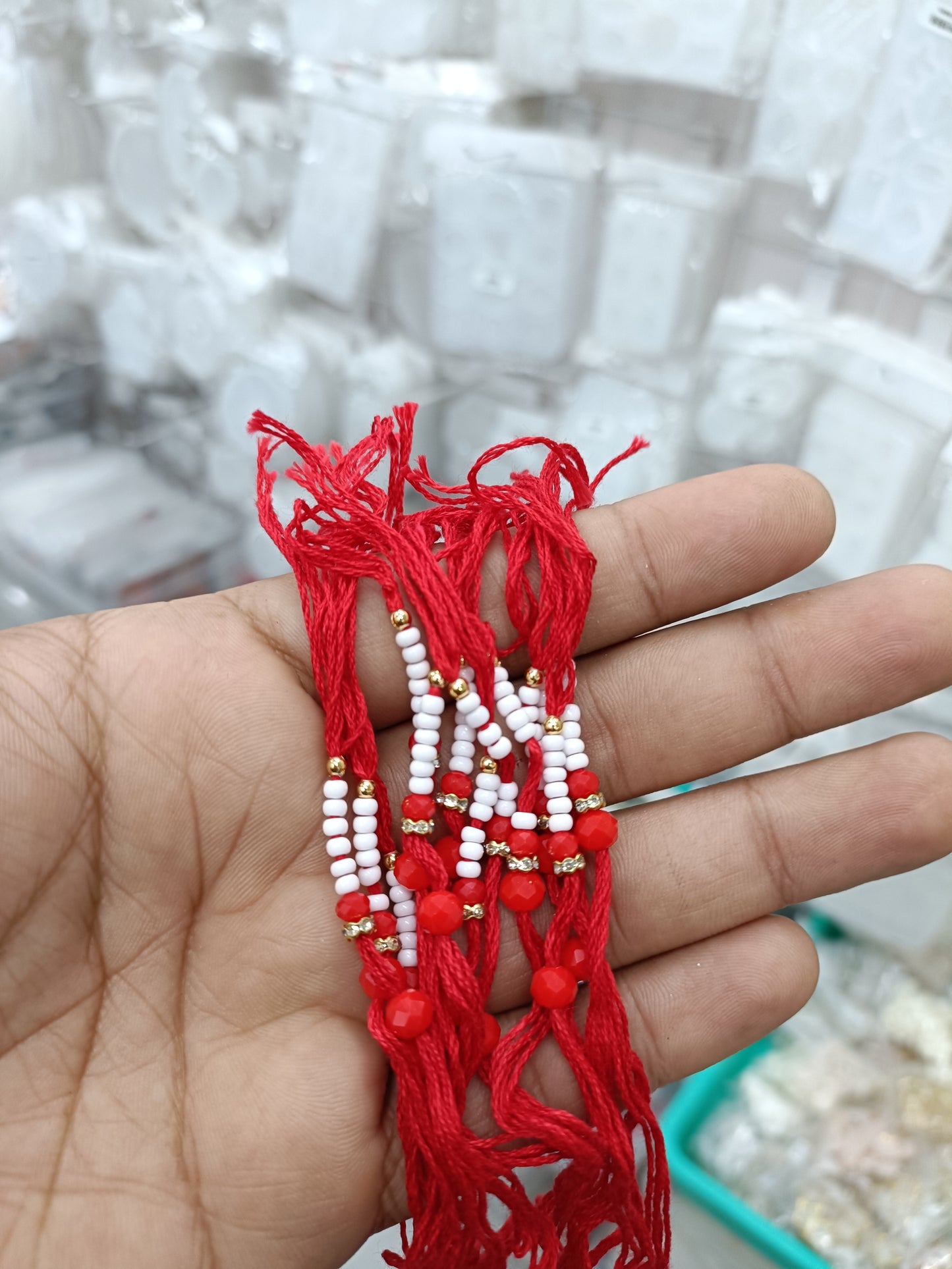 Red rakhi thread bracelet with white beads and small red accents