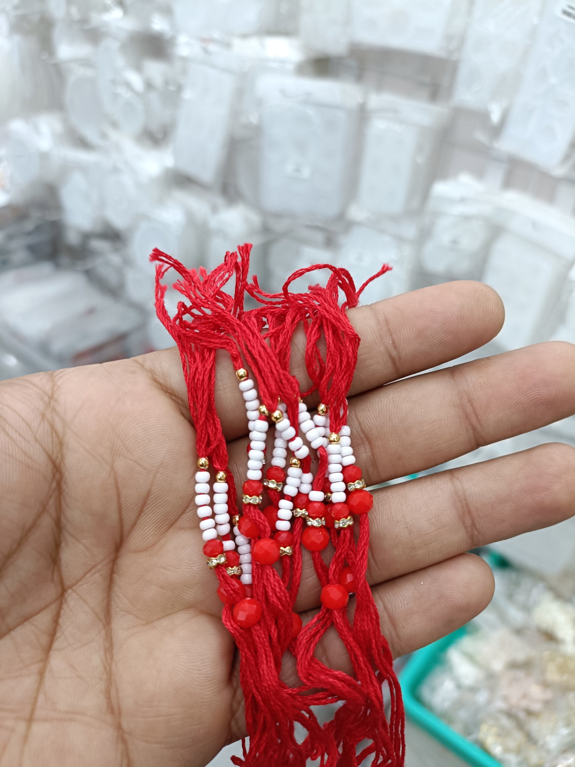 Red rakhi thread bracelet with white beads and small red accents