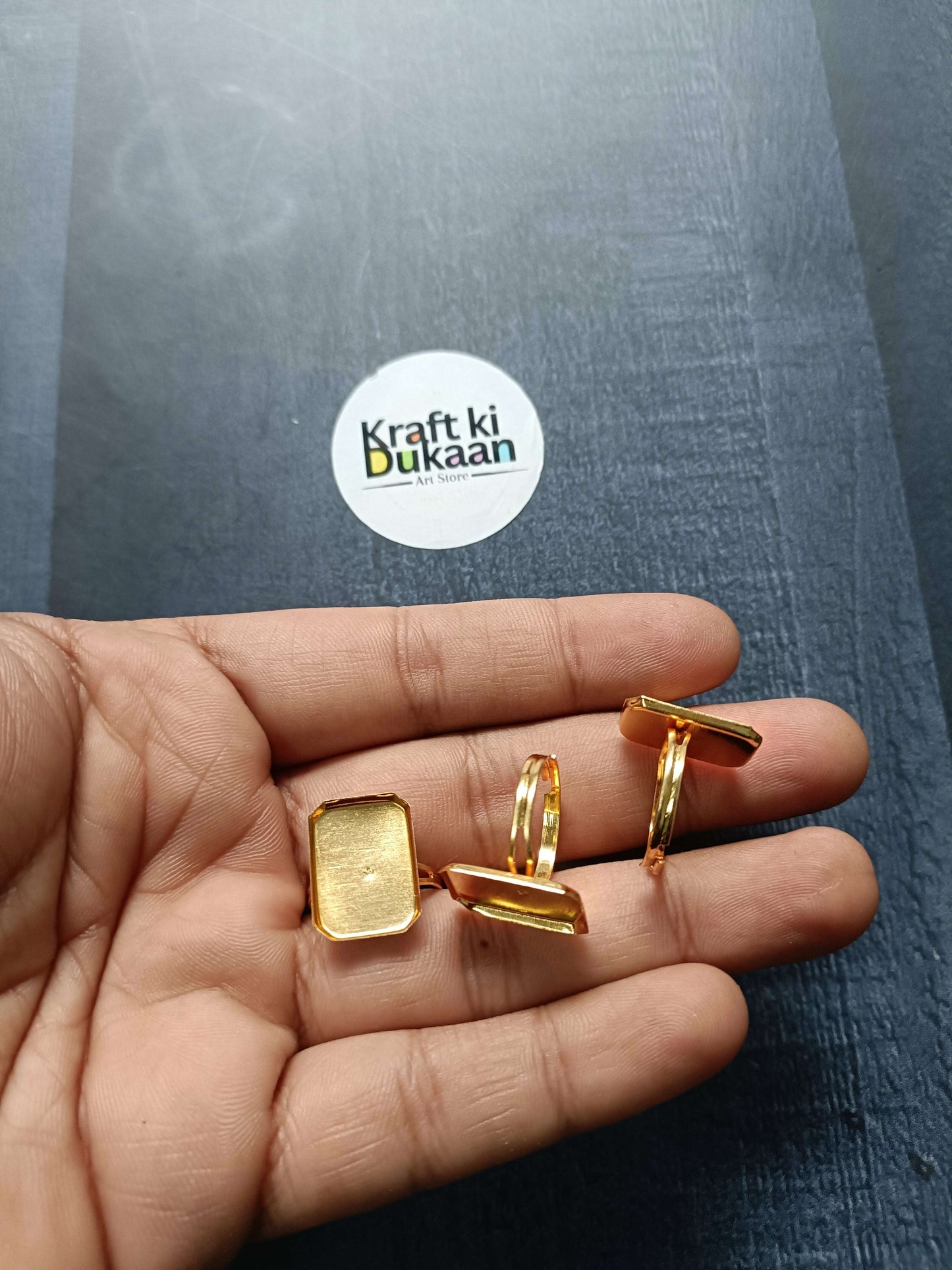 Gold ring bases with square top settings held in hand