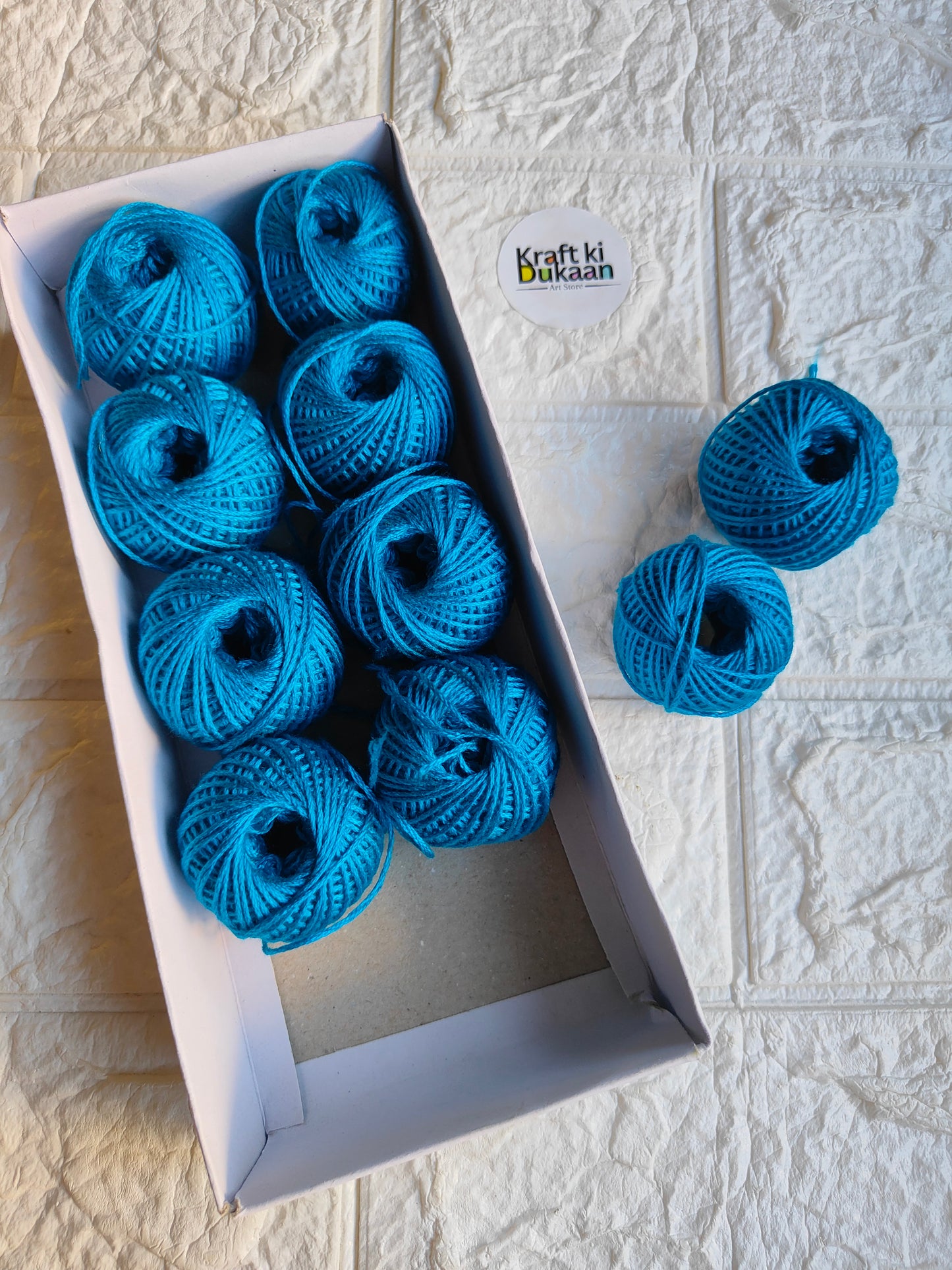 Rakhi thread roll with blue yarn balls in an open box and one loose ball