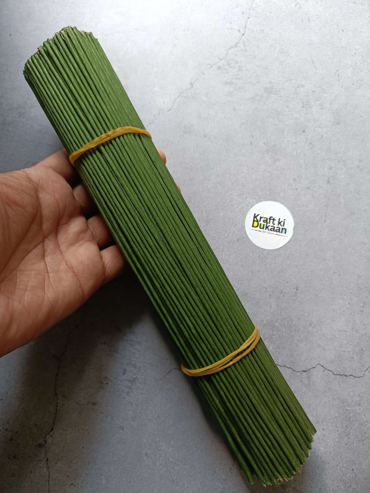 Green floral tape coated wire sticks bundle in hand, tan tie band