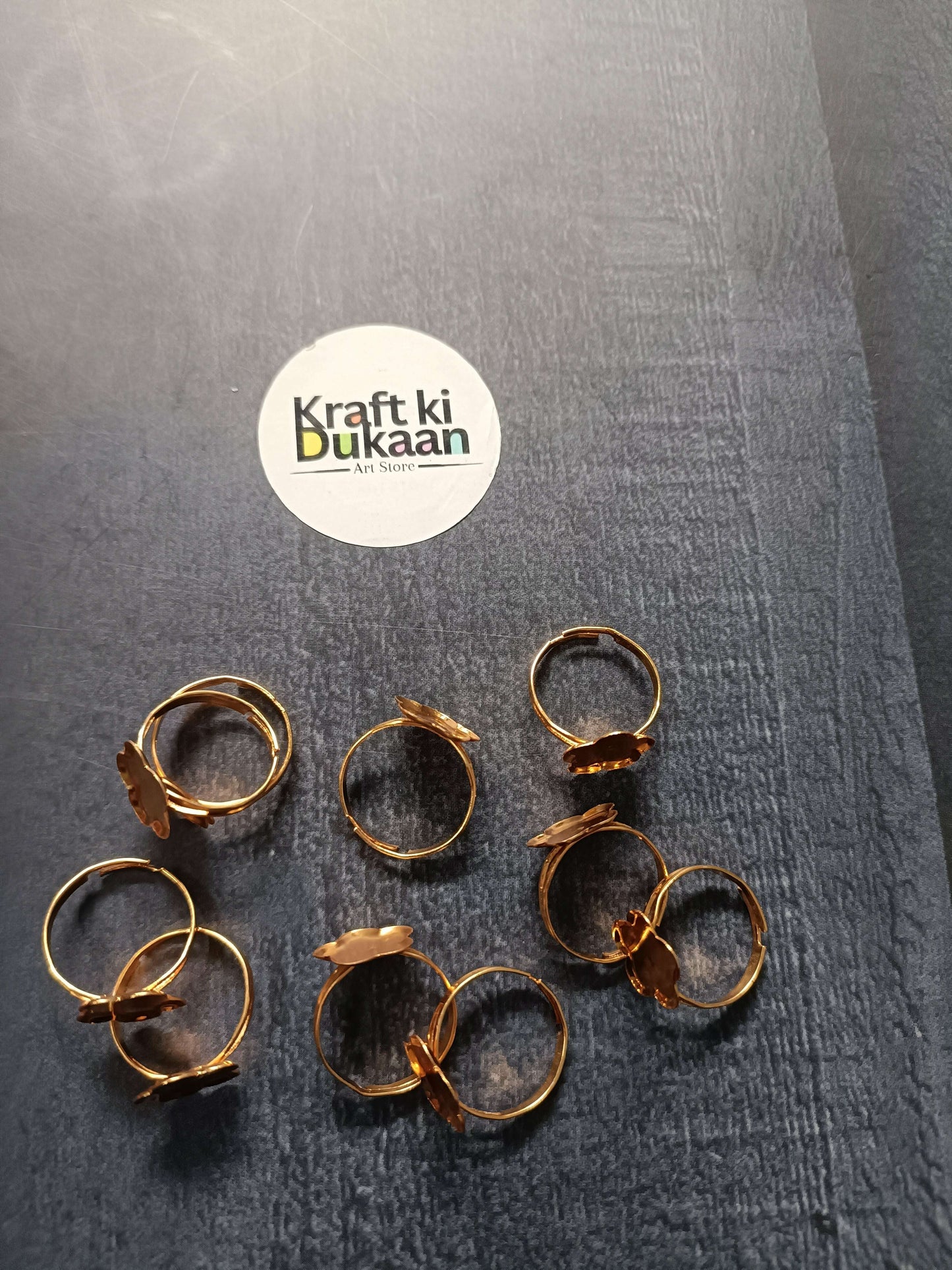 Gold-tone ring bases on surface: round and oval bezel open bands, assorted shapes