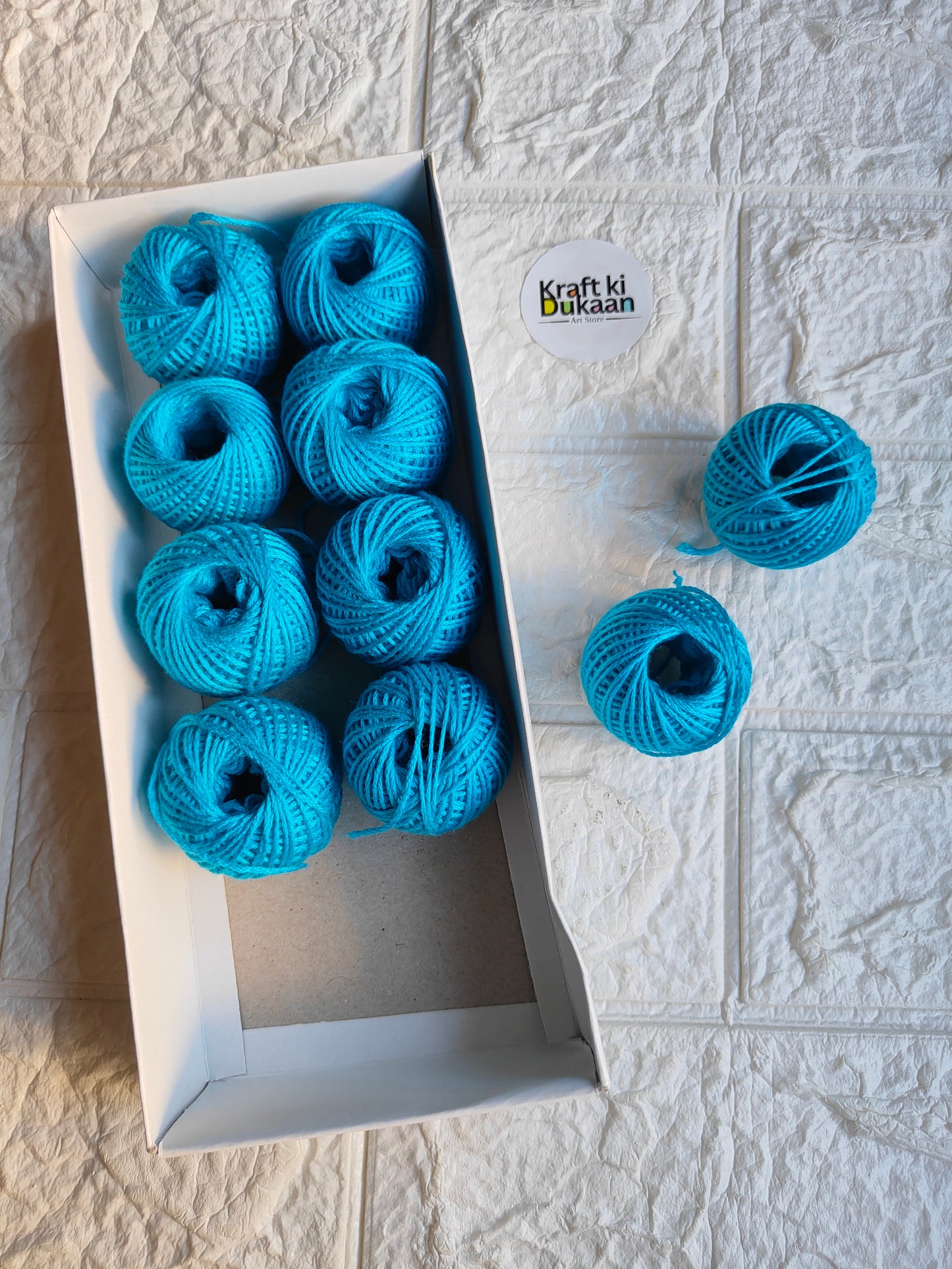 Rakhi thread roll set with turquoise yarn balls in an open cardboard box
