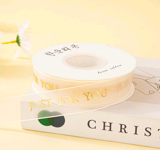 Off-white printed ribbon roll with repeating text and a small heart graphic