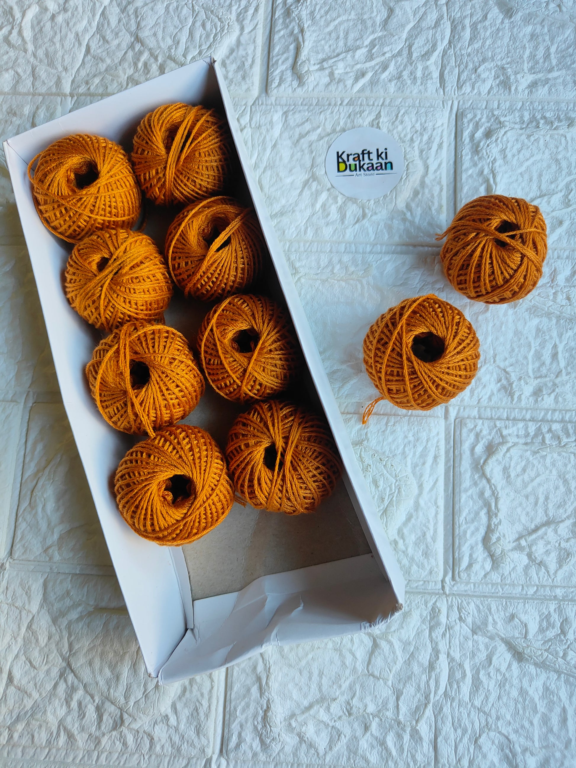 Rakhi thread roll with golden yellow yarn balls in an open box and one loose ball