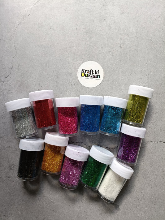 Chunky glitter powder set in assorted colors, shown in small jars with white caps.