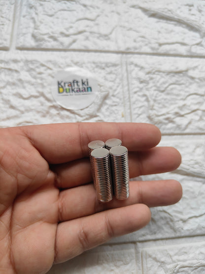 Round steel magnet pins, 10 x 1.5 mm, silver discs held in hand