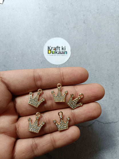 Gold crown pendant charms with sparkle rhinestones, five pieces held in hand