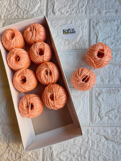 Rakhi thread roll with peach-orange yarn balls in an open box and one loose ball