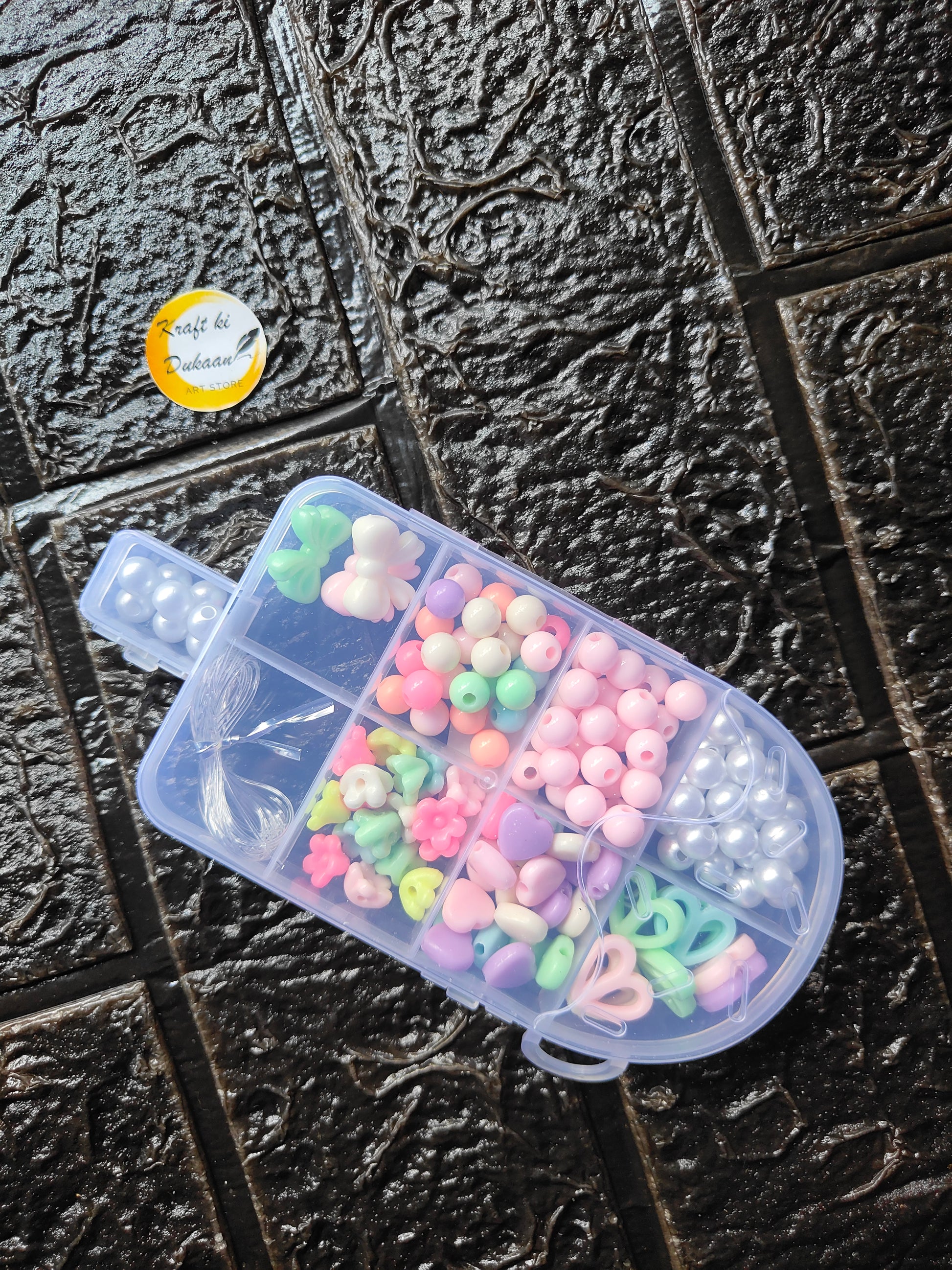 DIY bracelet beads kit: clear container of pastel beads, green and pink, plus white pearls
