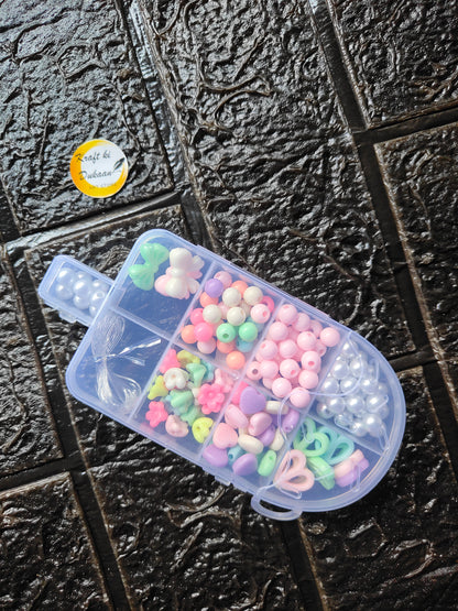 DIY bracelet beads kit: clear container of pastel beads, green and pink, plus white pearls