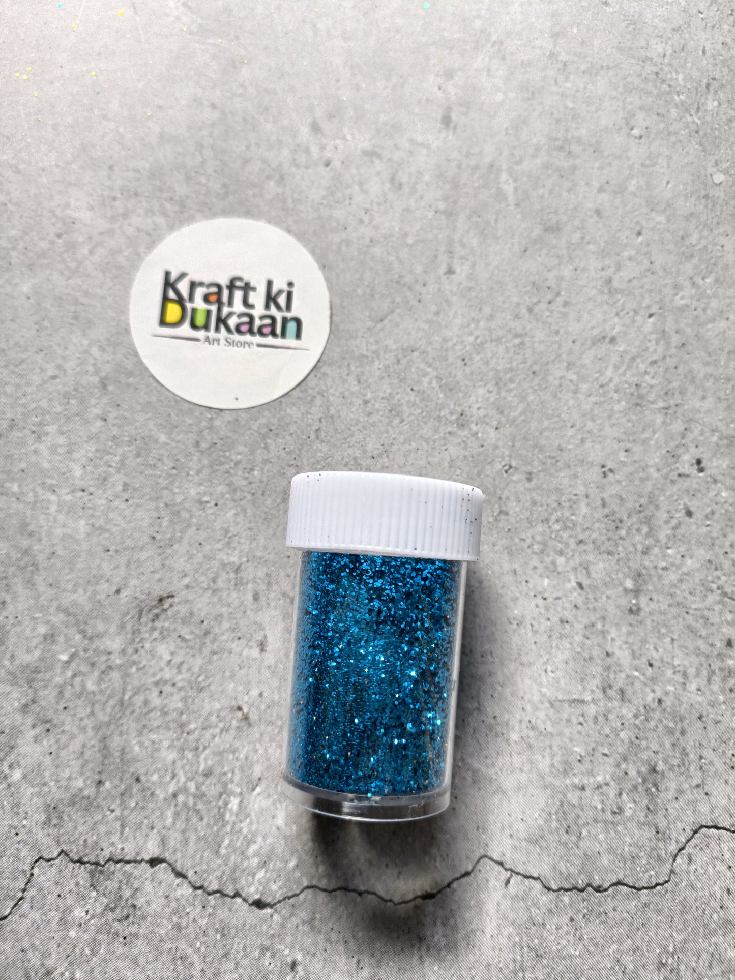 Blue chunky glitter powder jar with white lid.