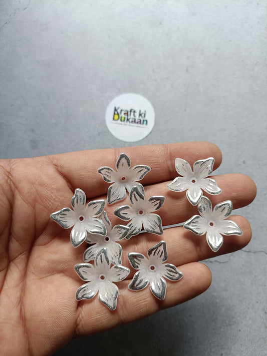 Silver flower-shaped beads, small flat backs, held in hand