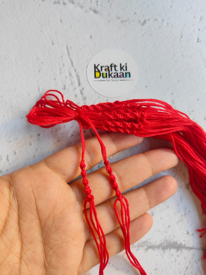Red rakhi dori threads held in hand, with loose braided ends
