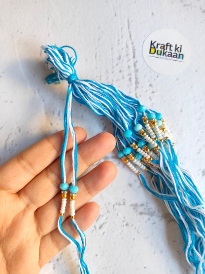 Blue rakhi thread with bead drops and knotted ends, held in hand