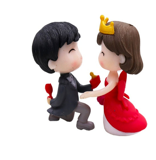 Miniature doll pair: black-haired figure in dark outfit, brown-haired figure in red dress