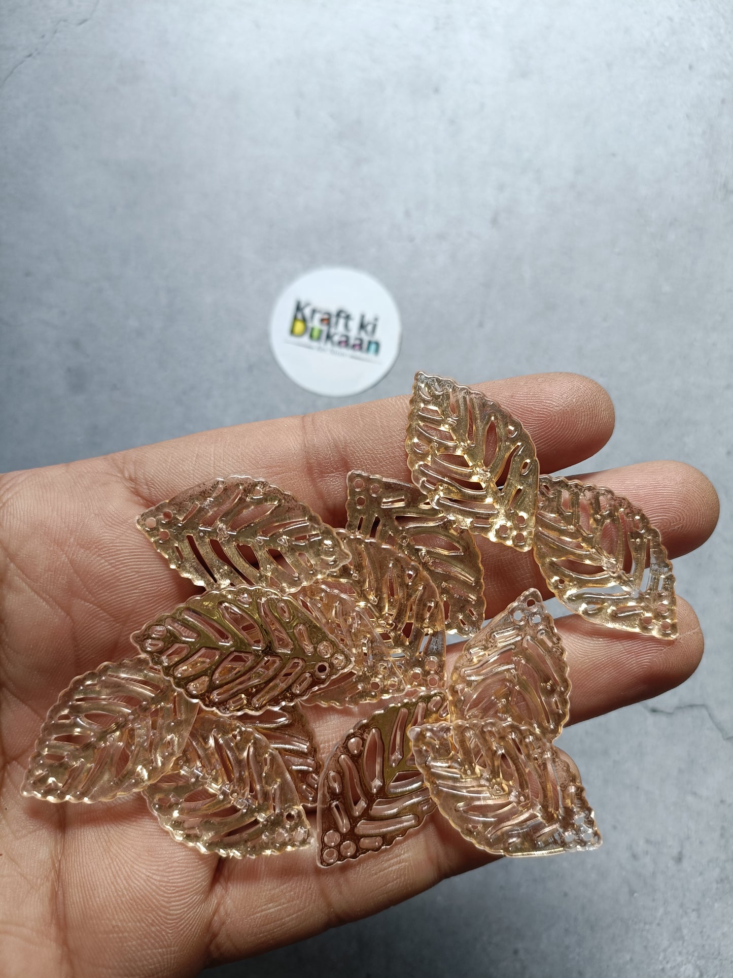 Gold leaf-shaped bead charms in hand, pack of 50