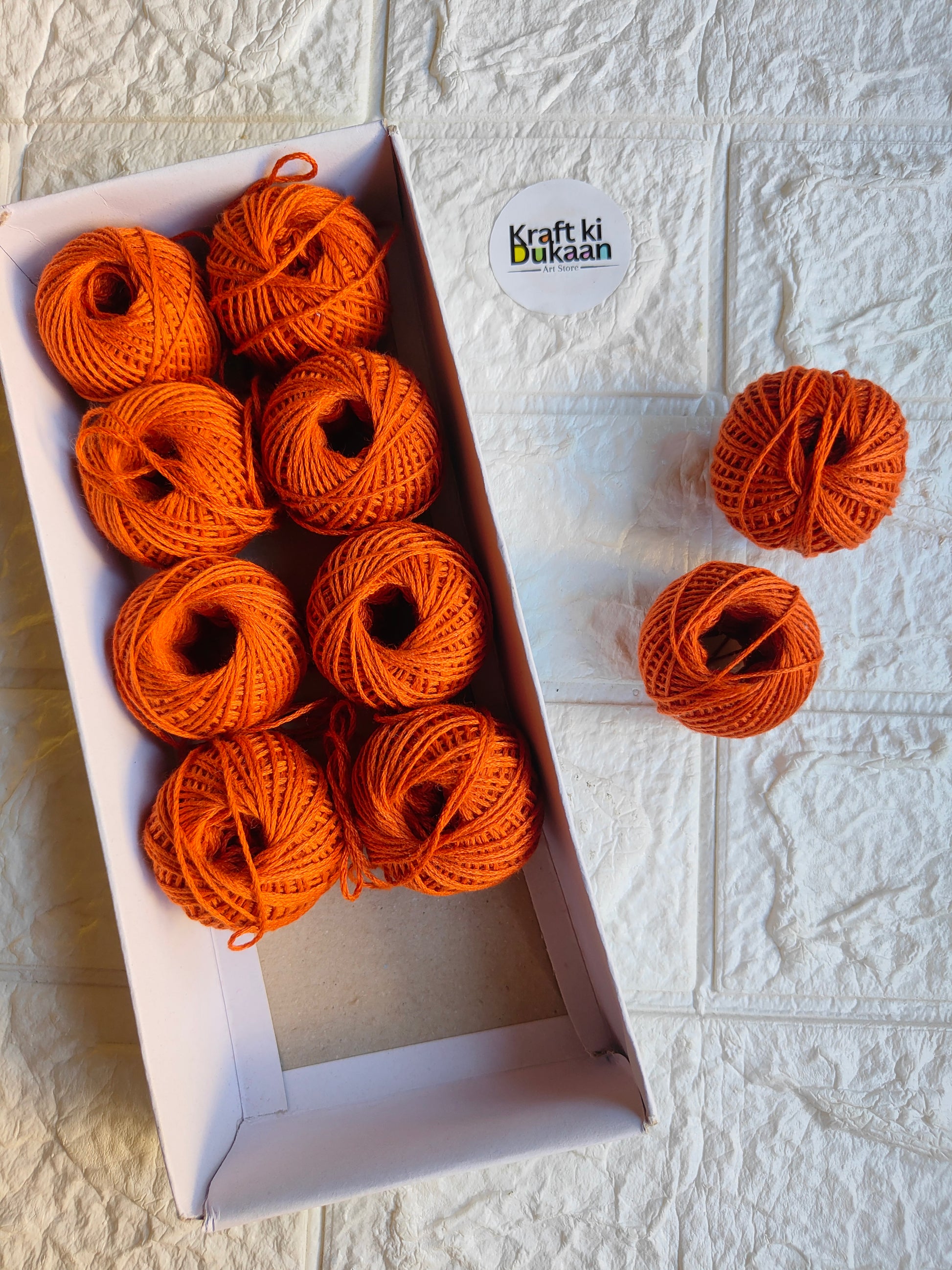Rakhi thread roll with orange yarn balls in an open box and one loose ball