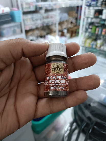 MICA pearl powder bottle, brown colorant, held in hand with screw cap.