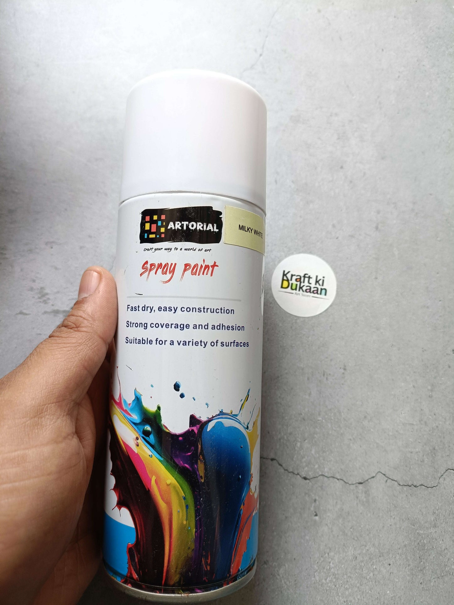Milky white spray paint can with colorful splatter artwork and “Kraft ki Dukaan” sticker