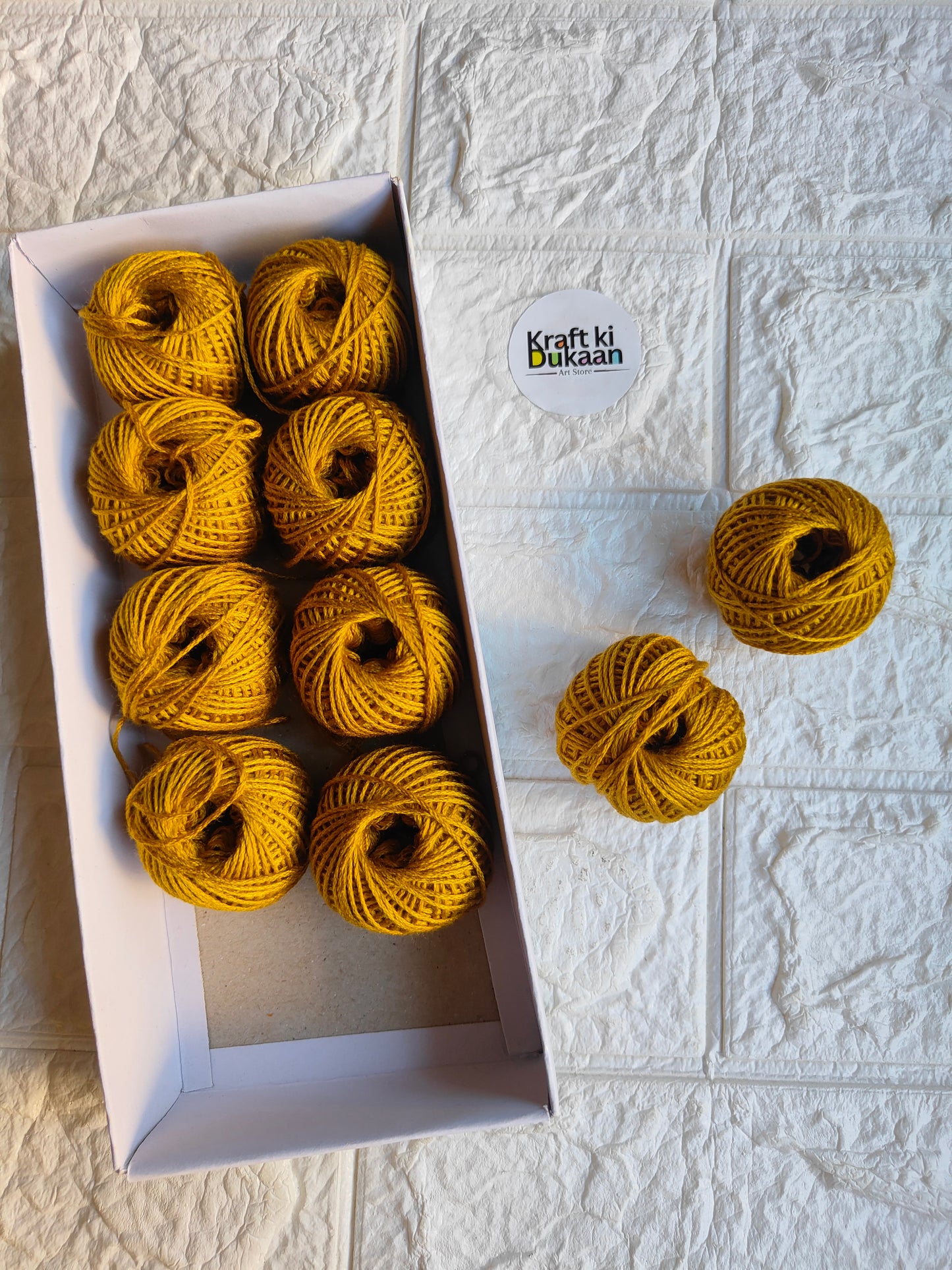 Rakhi thread roll with yellow-gold yarn balls in an open box and one loose ball