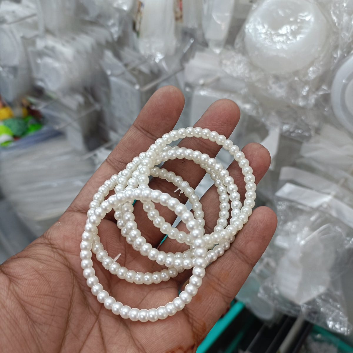 Large pearl ring made of smooth white beads, shown overlapping in a hand