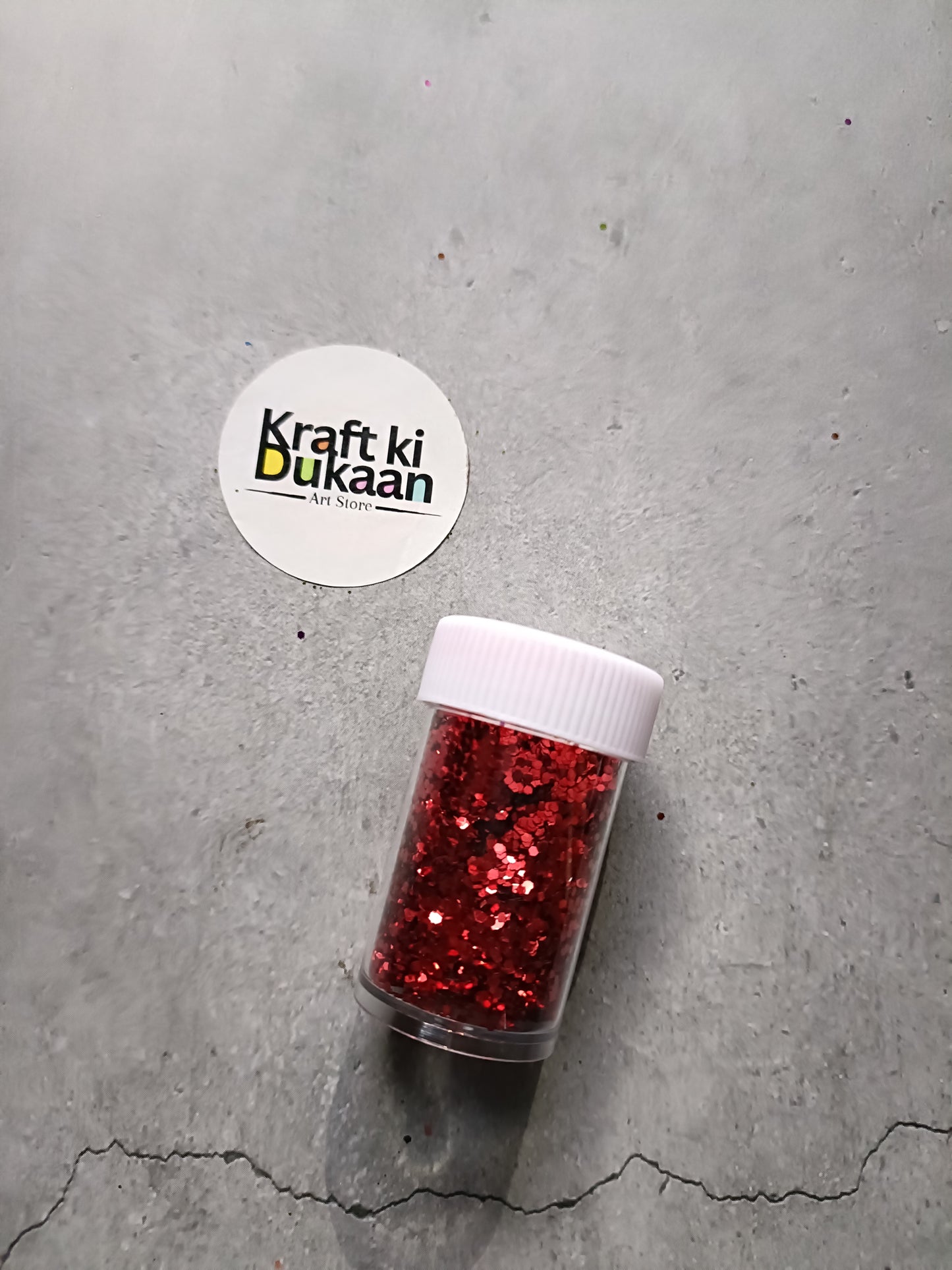 Hexagon-shaped glitter jar with red glitter flakes and white screw lid
