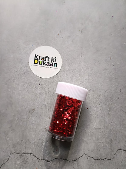 Hexagon-shaped glitter jar with red glitter flakes and white screw lid