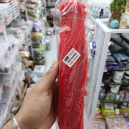 Red pipe cleaner bundle in clear plastic, label visible, held in hand