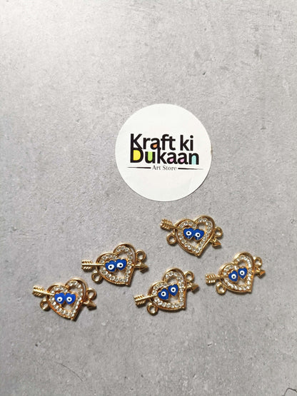 Five gold-tone heart evil-eye bracelet charms with blue centers, small hanging loops