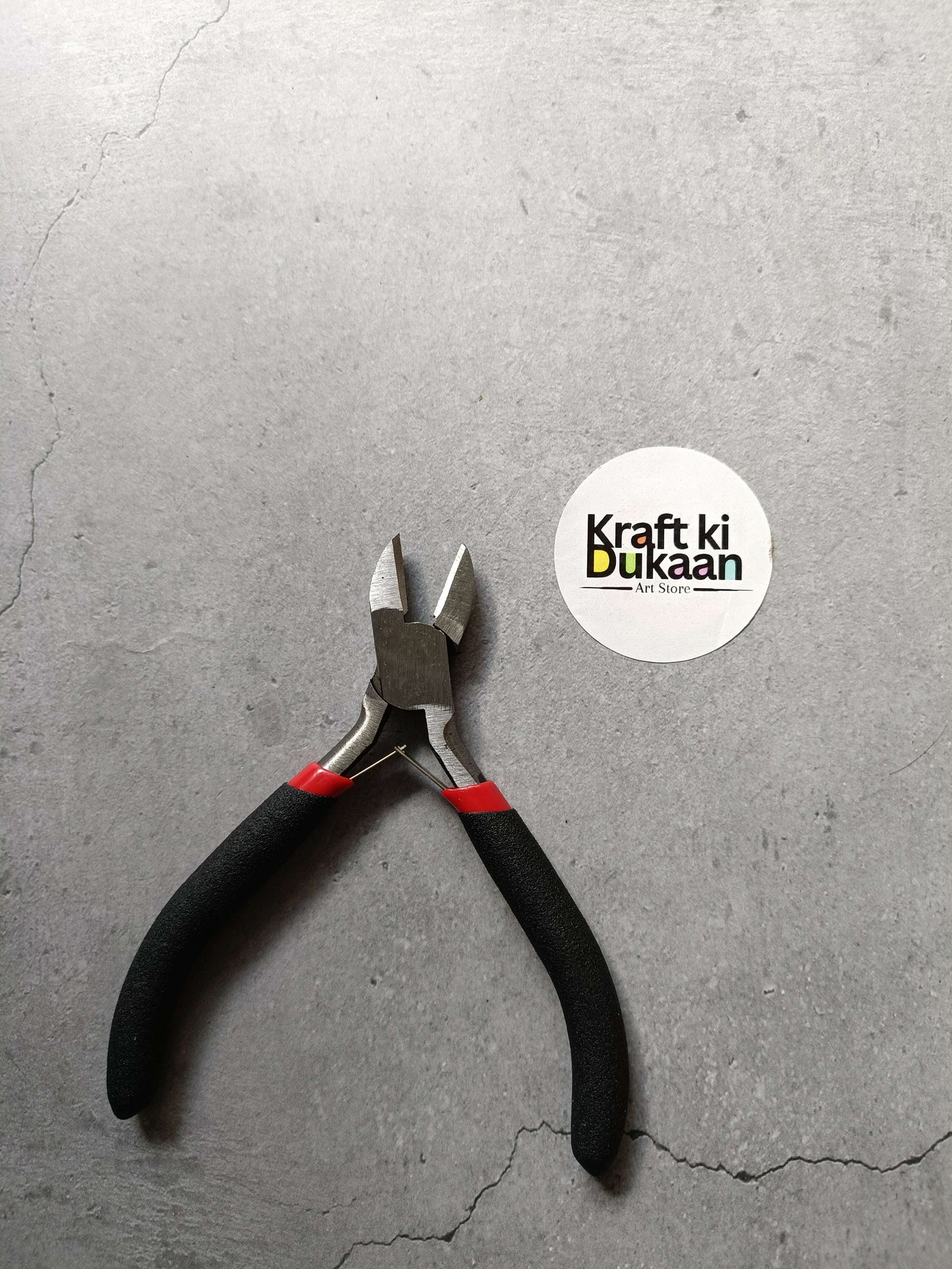 Black-handled pliers with red grips and metal cutting jaws