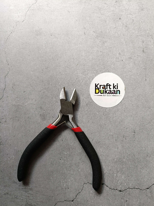 Black-handled pliers with red grips and metal cutting jaws
