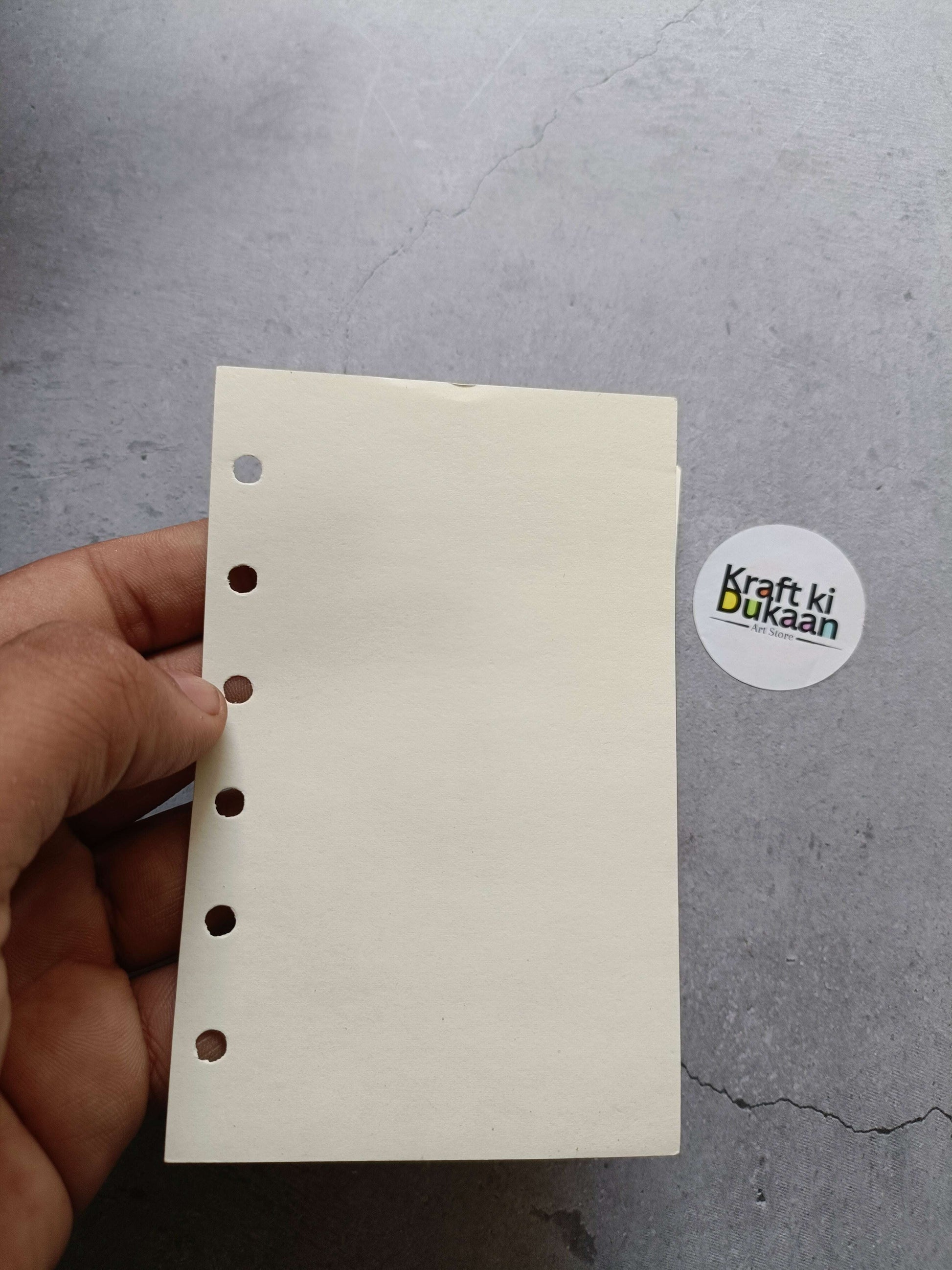 Hand holding cream note pages with punched holes, 8.3x13cm