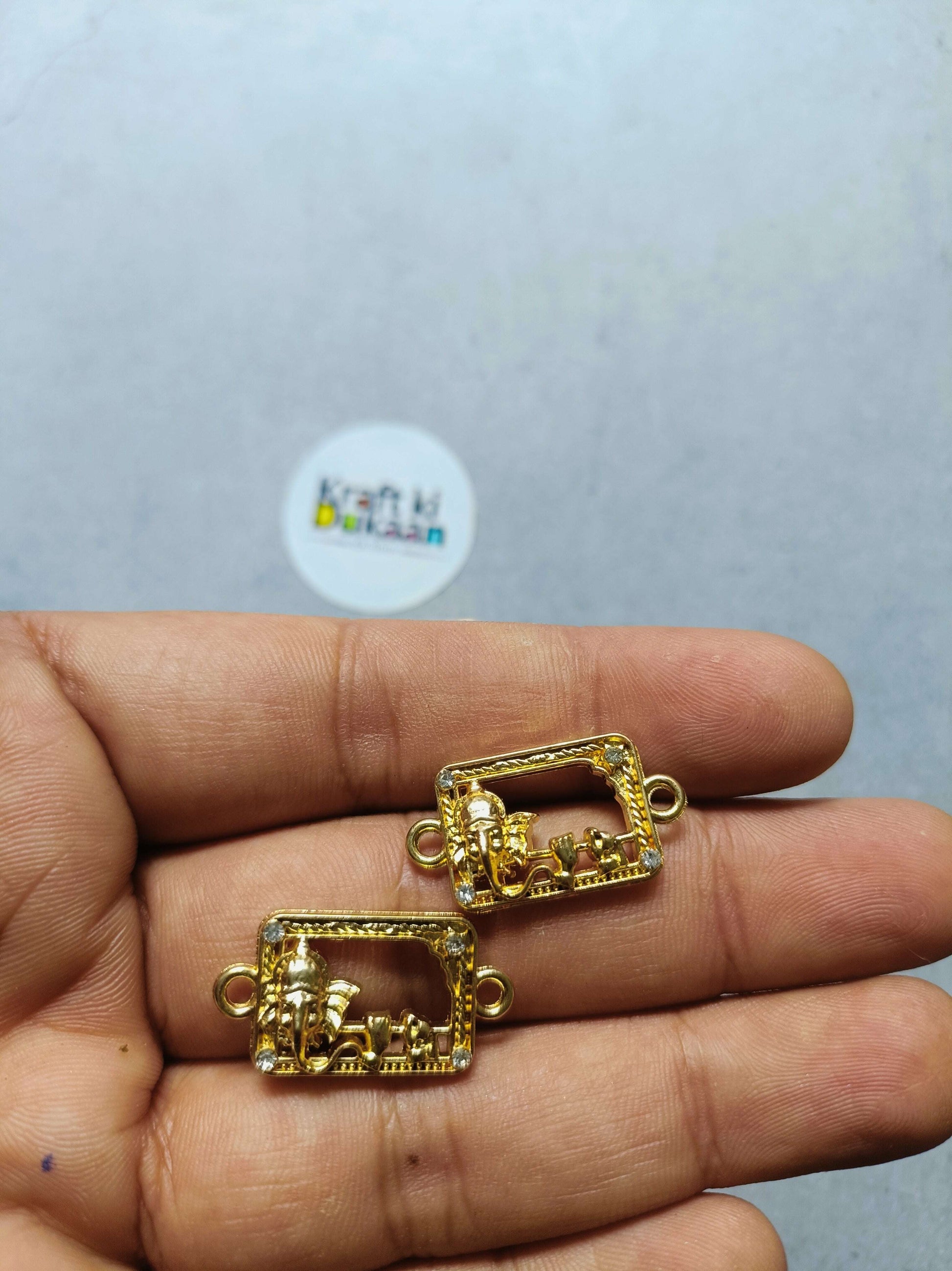 Gold-tone rakhi bracelet bezel charm with square frame and loop ends shown on hand