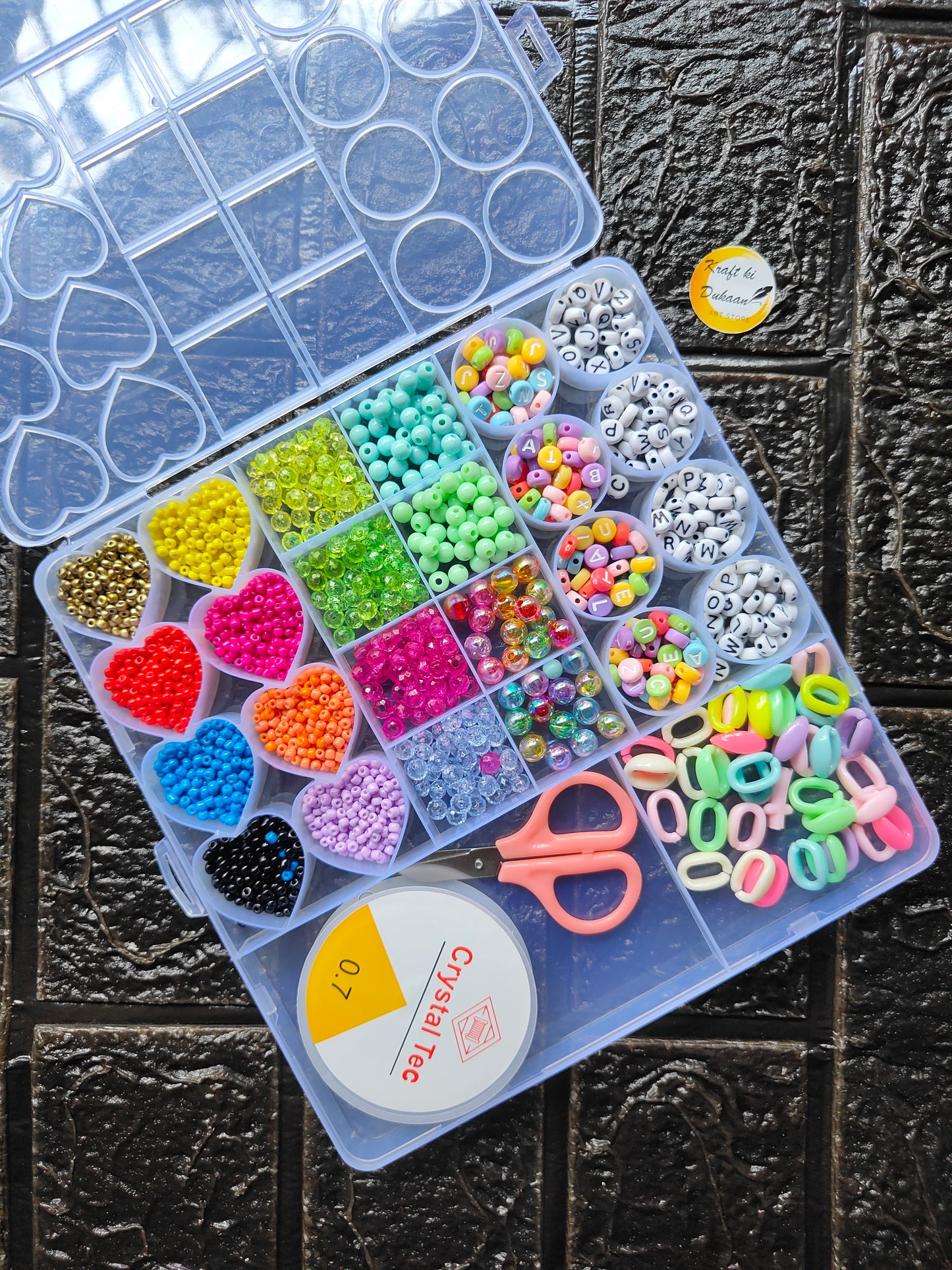 DIY bracelet beads kit with bead tubes, heart beads, and pink scissors in organizer