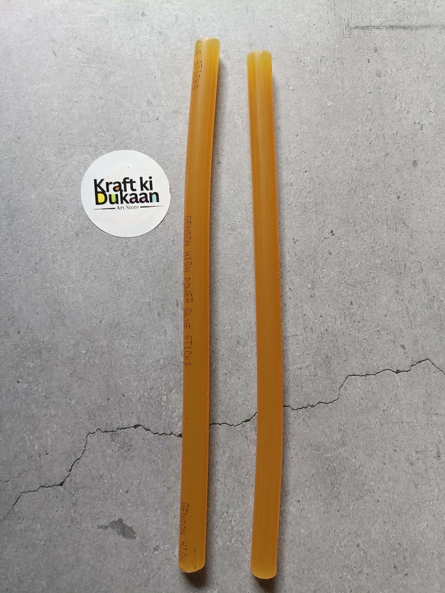 Two amber hot melt glue sticks, cylindrical with printed markings