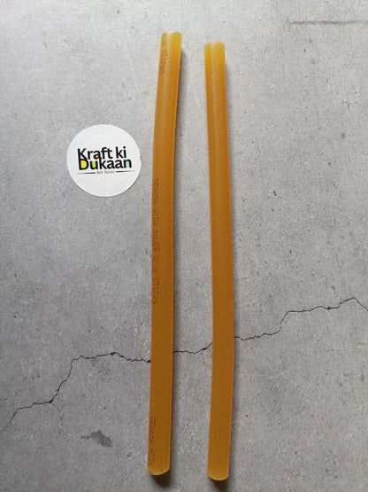 Two amber hot melt glue sticks, cylindrical with printed markings