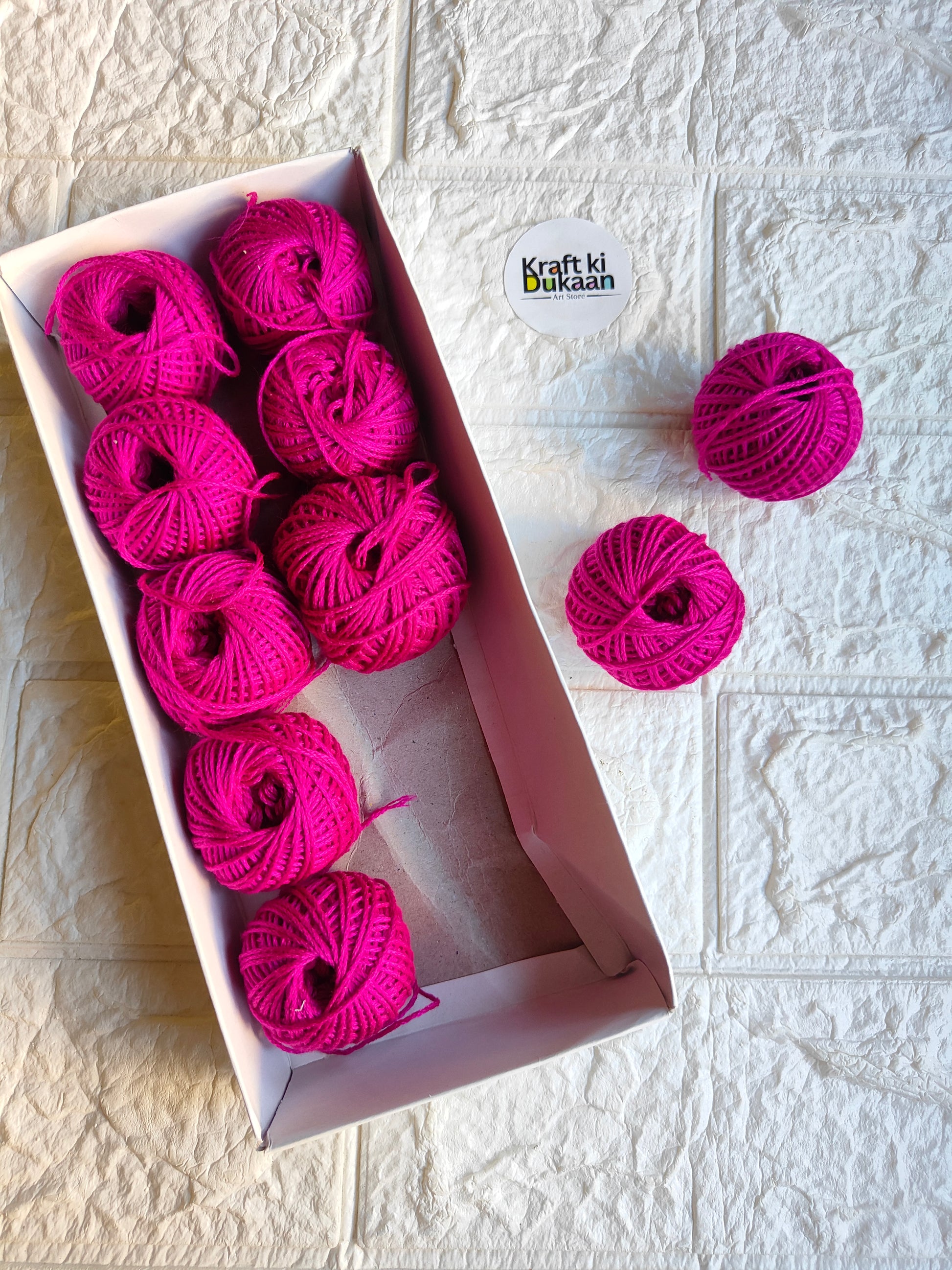 Rakhi thread roll with fuchsia pink yarn balls in an open box and one loose ball