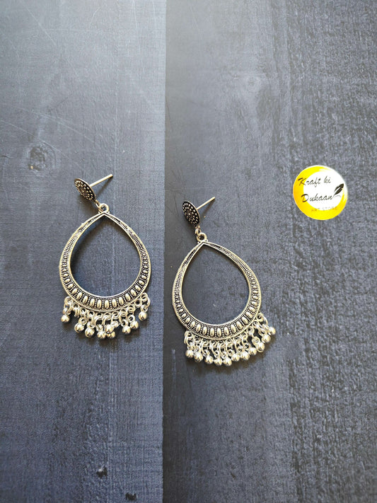 Silver jhumka earrings with teardrop design, filigree edging, and dangling tassel pieces