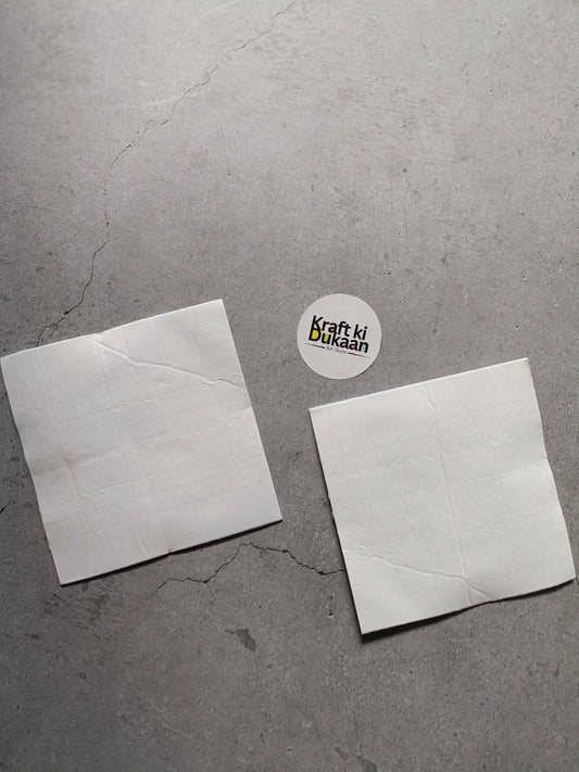 Two square white foam tape adhesive pads with small dots pattern, side by side