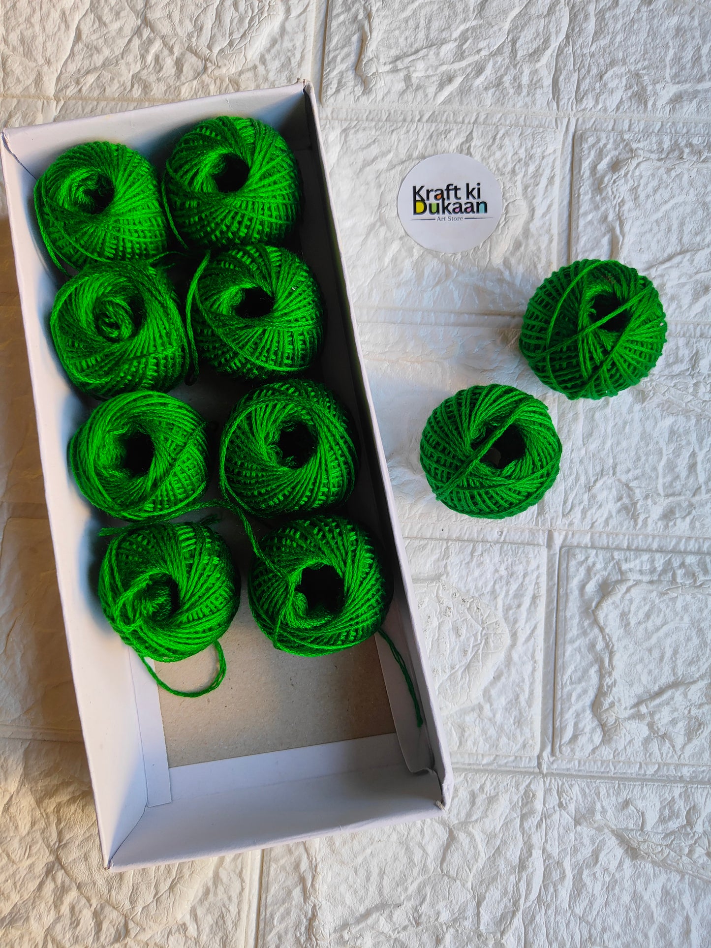 Rakhi thread roll with green yarn balls in an open box and one loose ball